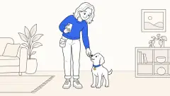 A trainer rewards a small puppy beside her leg while using a smartphone as a clicker in a calm living room.